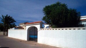 A gated entrance with a white wall and a decorative border, leading to a building with a red-tiled roof. - Villa Recaredo - Chalet con piscina privada en Vinaròs - Ref. 1600 (Vinaròs)