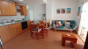 Un espacio habitable compacto con cocina, comedor y sofá.