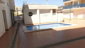Zona de piscina exterior con suelo de baldosas y una piscina pequeña.