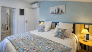 A hotel room with a bed, a painting of sailboats on the wall, a bedside lamp, and a door leading to a bathroom. - 1 bedroom lovely home in Saujon (Saujon)
