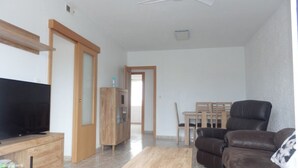 Un salon avec un téléviseur, un meuble en bois, un canapé en cuir marron et un ventilateur de plafond.