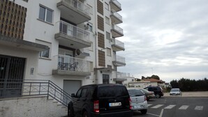 Un immeuble résidentiel à plusieurs étages doté de balcons, un espace de stationnement avec plusieurs voitures et un ciel dégagé.