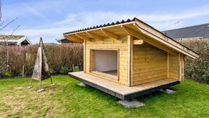Una cabana de fusta amb teulada inclinada, un petit porxo i una porta.