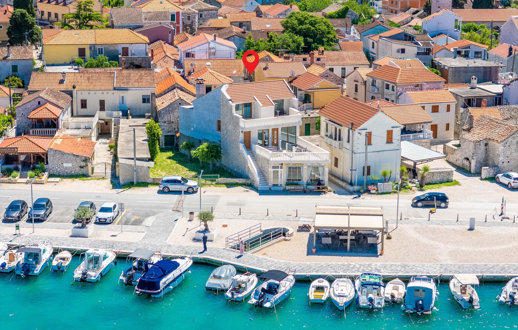 Une ville côtière dotée d’un port de plaisance, de bâtiments en pierre et d’un hôtel moderne avec une terrasse.