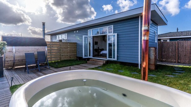A modern house with a hot tub, wooden deck, and a fenced backyard. - Cozy home in Vinkeveen with sauna (Vinkeveen)