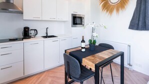 A modern kitchen with white cabinets, a built-in microwave, a coffee maker, and a wine bottle on the counter. - Cozy home in Vinkeveen with sauna (Vinkeveen)