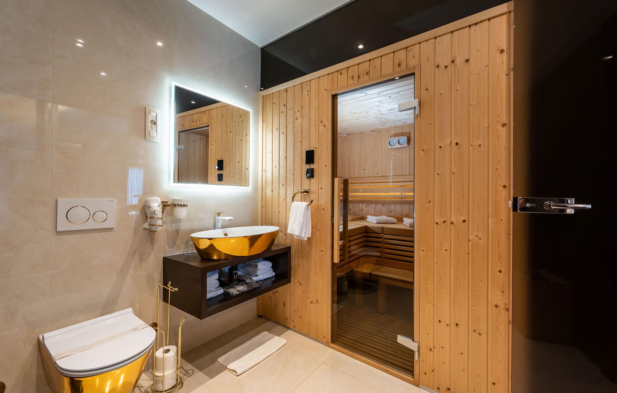 Um banheiro moderno com sauna de madeira, pia dourada e um espelho grande.