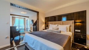 A modern hotel room with a large bed, a desk, and a view of the outdoors.