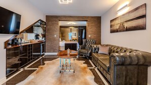 A modern living room with a leather sofa, a coffee table, and a flat-screen TV mounted on the wall.
