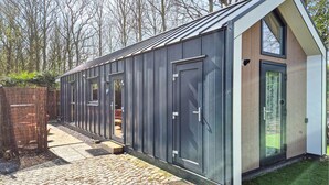 A modern, single-story building with a large glass door and windows, a sloped roof, and a brick pathway leading to the entrance. - Beautiful home in Heinkenszand (Heinkenszand)