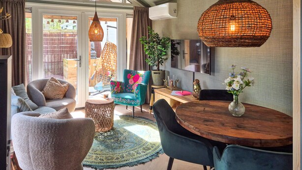 A cozy living room with a sofa, chairs, a wooden dining table, and a hanging light fixture. - Beautiful home in Heinkenszand (Heinkenszand)