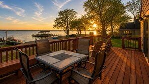 A wooden deck with outdoor furniture, a view of the water, and a dock with boats. - Geneva Lakefront Retreat | Kayaks | Dome Hockey (Geneva)