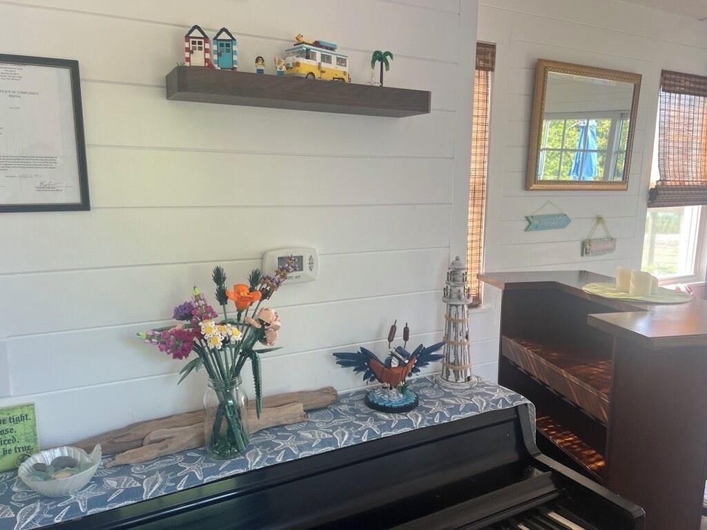 A room with a fireplace, a shelf with decorative items, a vase with flowers, and a framed certificate on the wall.