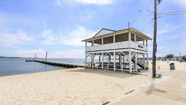 A beach house with a covered deck and a pier extending into the water.