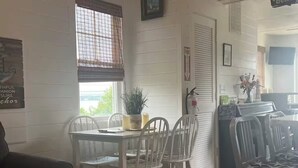 A dining area with a table and chairs, a potted plant, and a fire extinguisher on the wall.