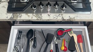 Una cucina con un fornello e un cassetto pieno di utensili.
