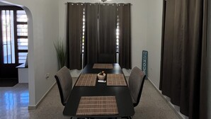 Un'elegante sala da pranzo moderna con un tavolo nero, sedie grigie, un lampadario originale e tende scure.