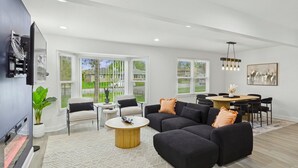 Una sala de estar moderna con un sofá modular, una mesa de centro redonda y un comedor con mesa y sillas.
