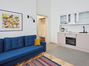 Relax in this cozy living space with a sofa, colorful rug, and kitchenette, perfect for a convenient stay.