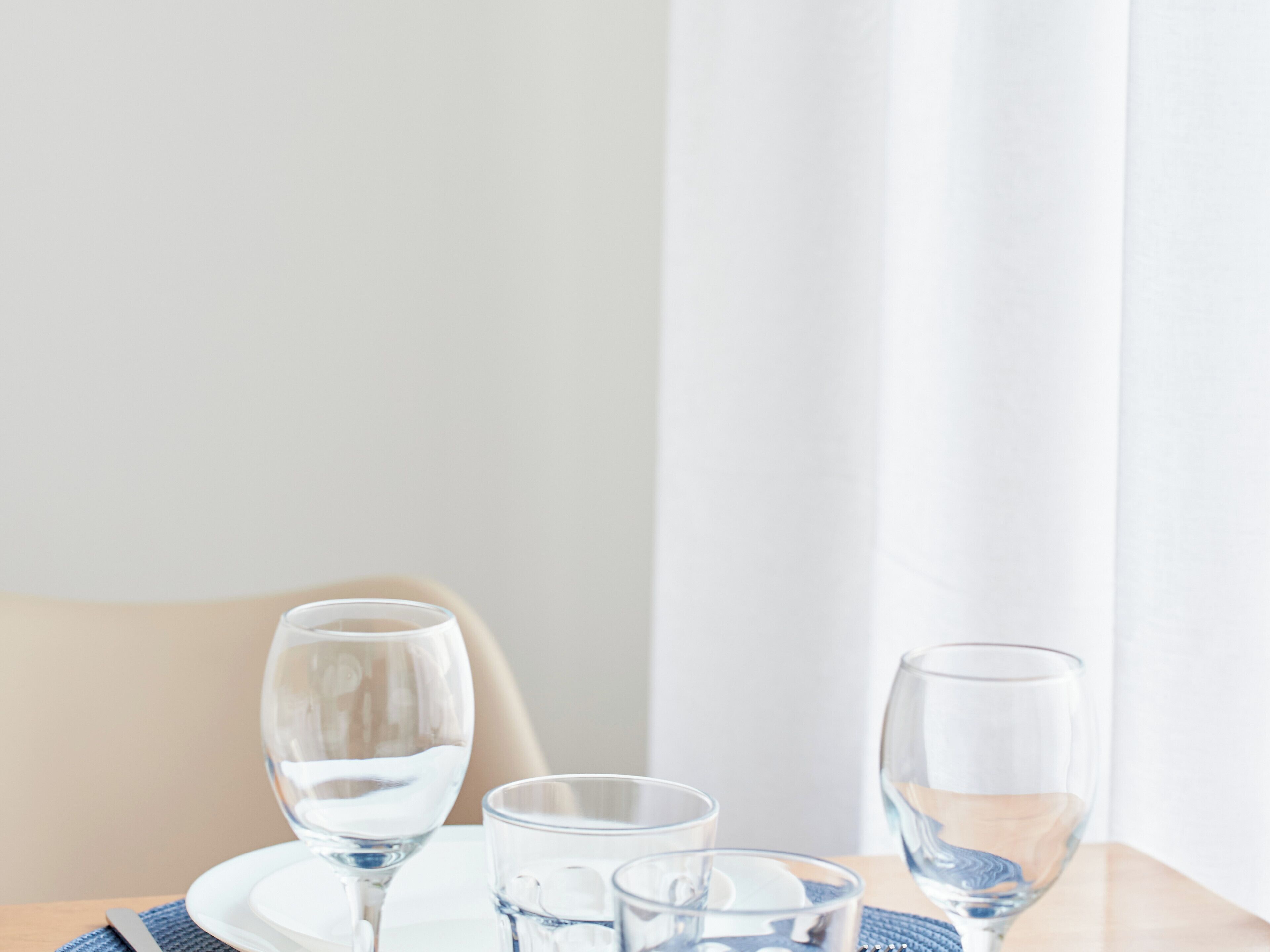 Een tafel met drie glaasjes water, een bord en een servet.