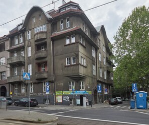 Classic building with a corner entrance, balconies, and large windows, offering parking and pedestrian access.