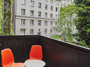 Enjoy the view from this balcony with a table and two chairs.