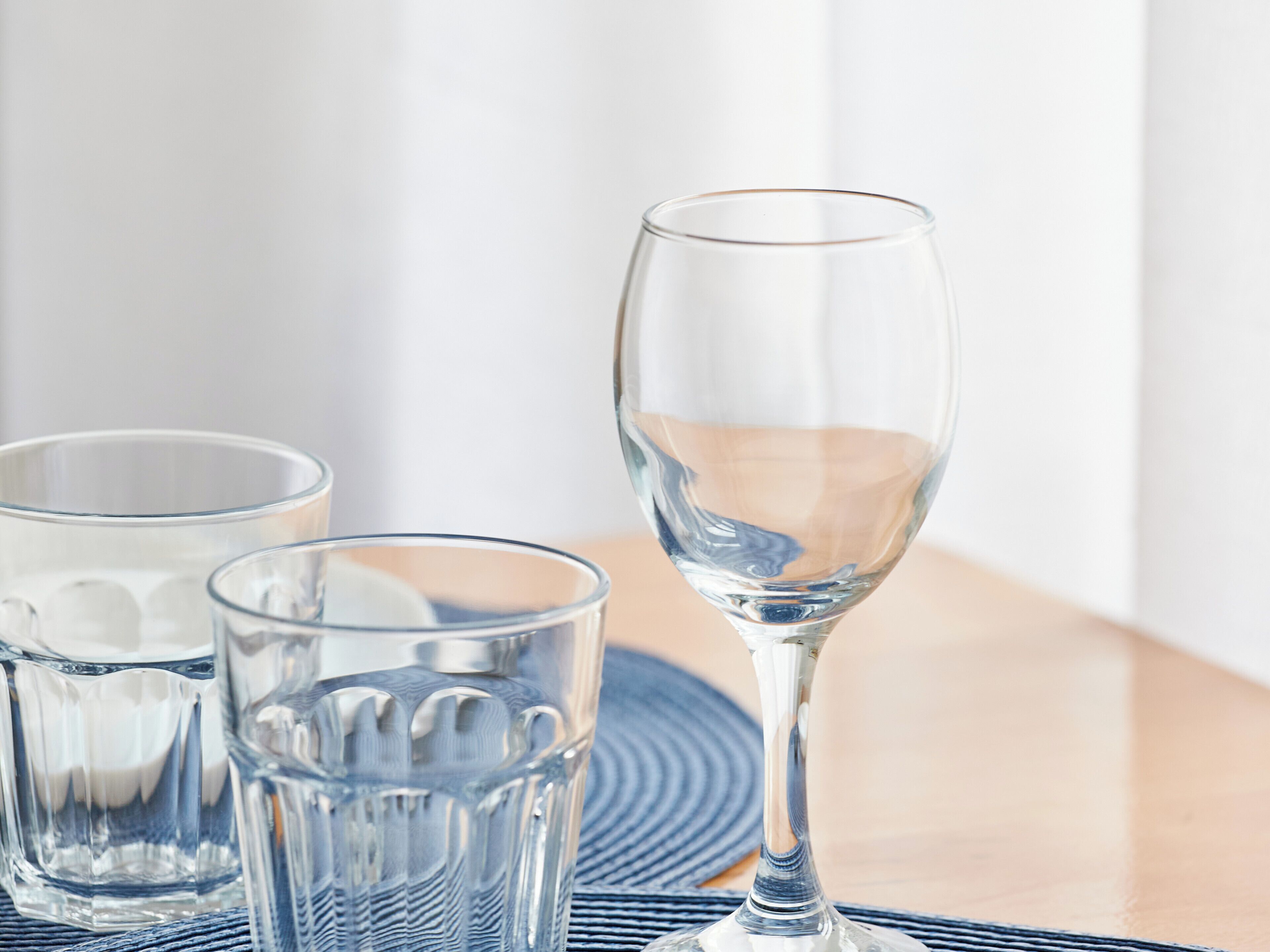 Trois verres en verre transparent posés sur un tapis tissé.