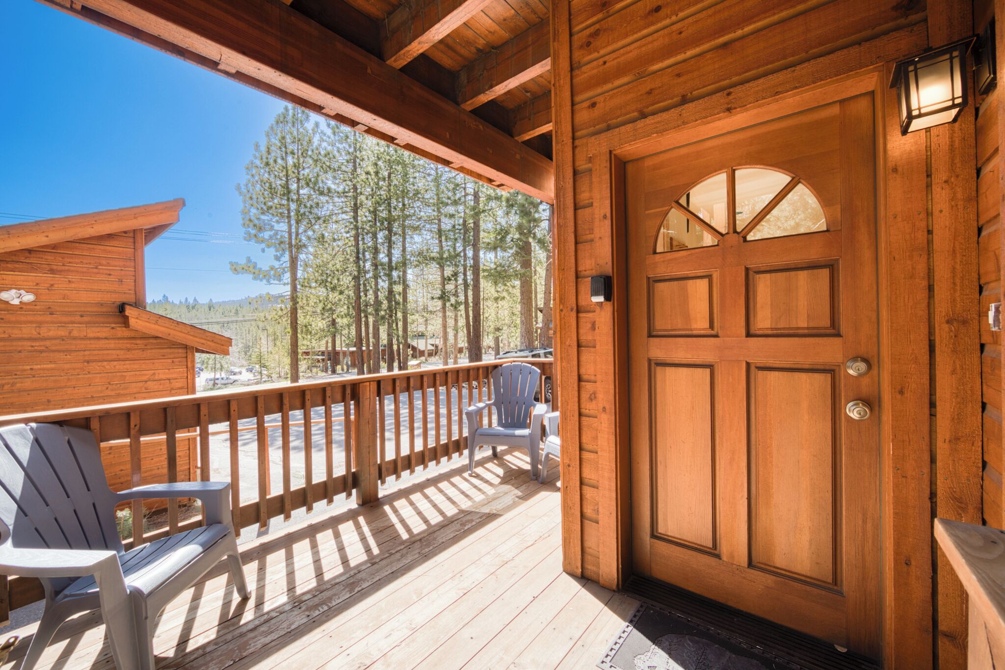 Eine Holzlaube mit Veranda, zwei Adirondack-Stühlen und einer großen Holztür.