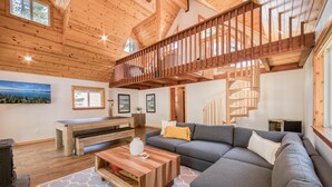 A spacious living room with a large gray sectional sofa, a wooden coffee table, and a staircase leading to an upper level. - Hillcrest at Tahoe Donner by Tahoe Getaways - 3BR Pet-Friendly w/ Pool Table & Ping Pong (Truckee)