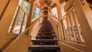 A wooden staircase with a handrail, leading up to a covered area with a view of trees. - Hillcrest at Tahoe Donner by Tahoe Getaways - 3BR Pet-Friendly w/ Pool Table & Ping Pong (Truckee)
