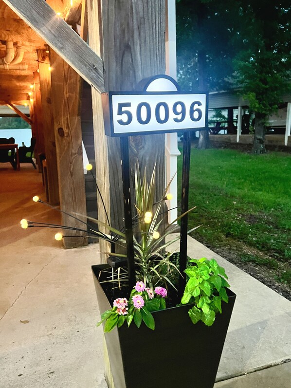A house number sign, a wooden structure, and a planter with flowers.