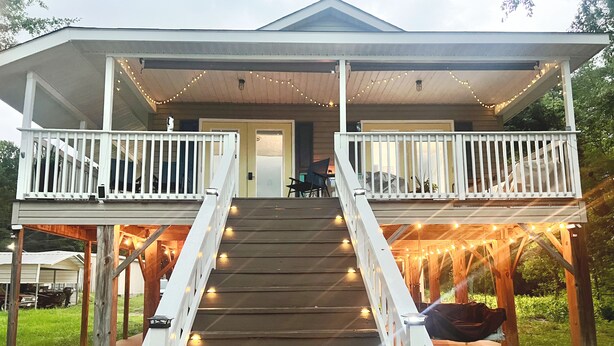 A two-story house with a porch, a staircase, and string lights.