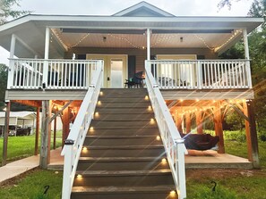 A two-story house with a porch, a staircase, and string lights.