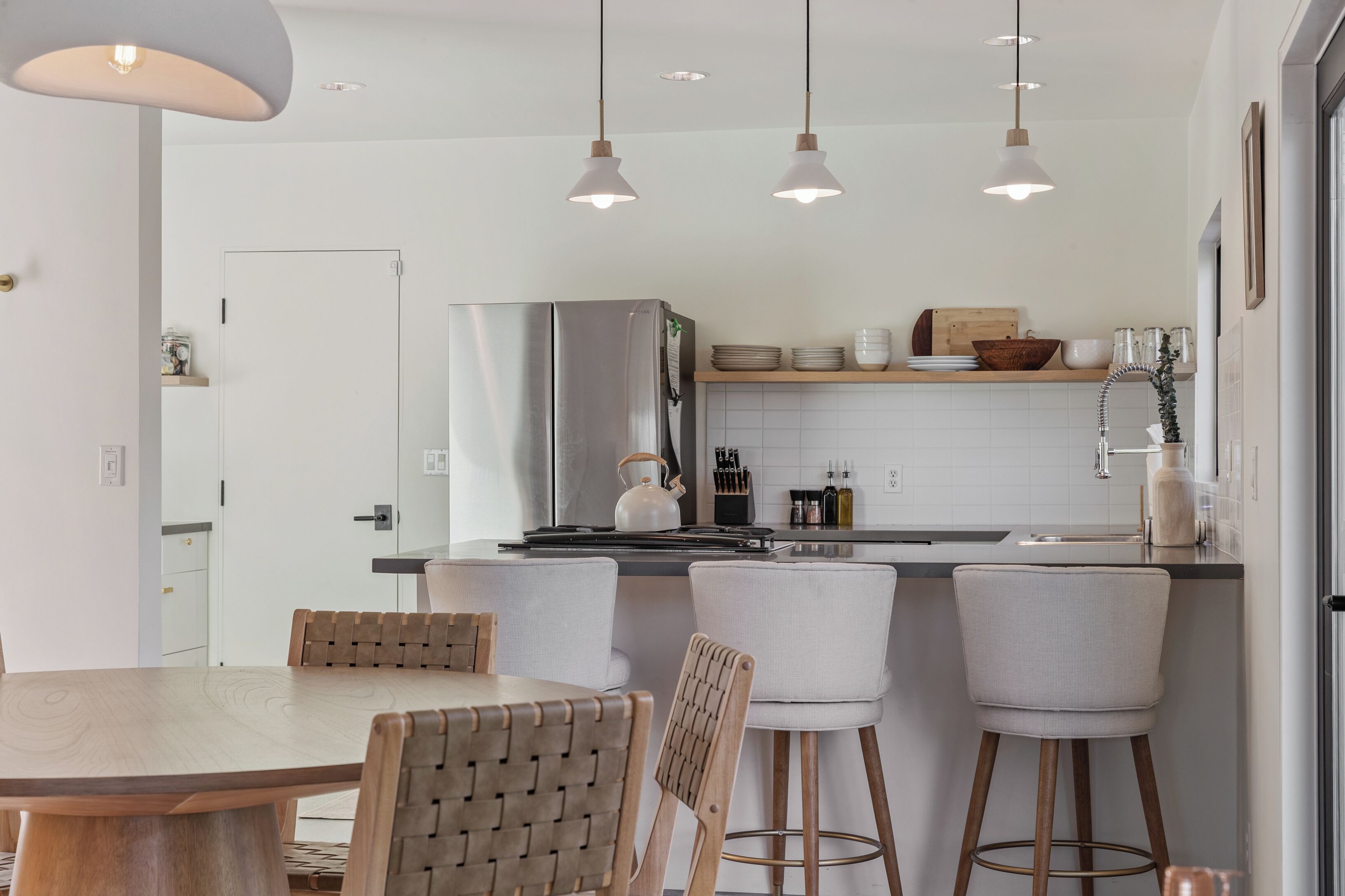 Une cuisine moderne dotée d’un îlot central, de tabourets de bar et de luminaires suspendus.