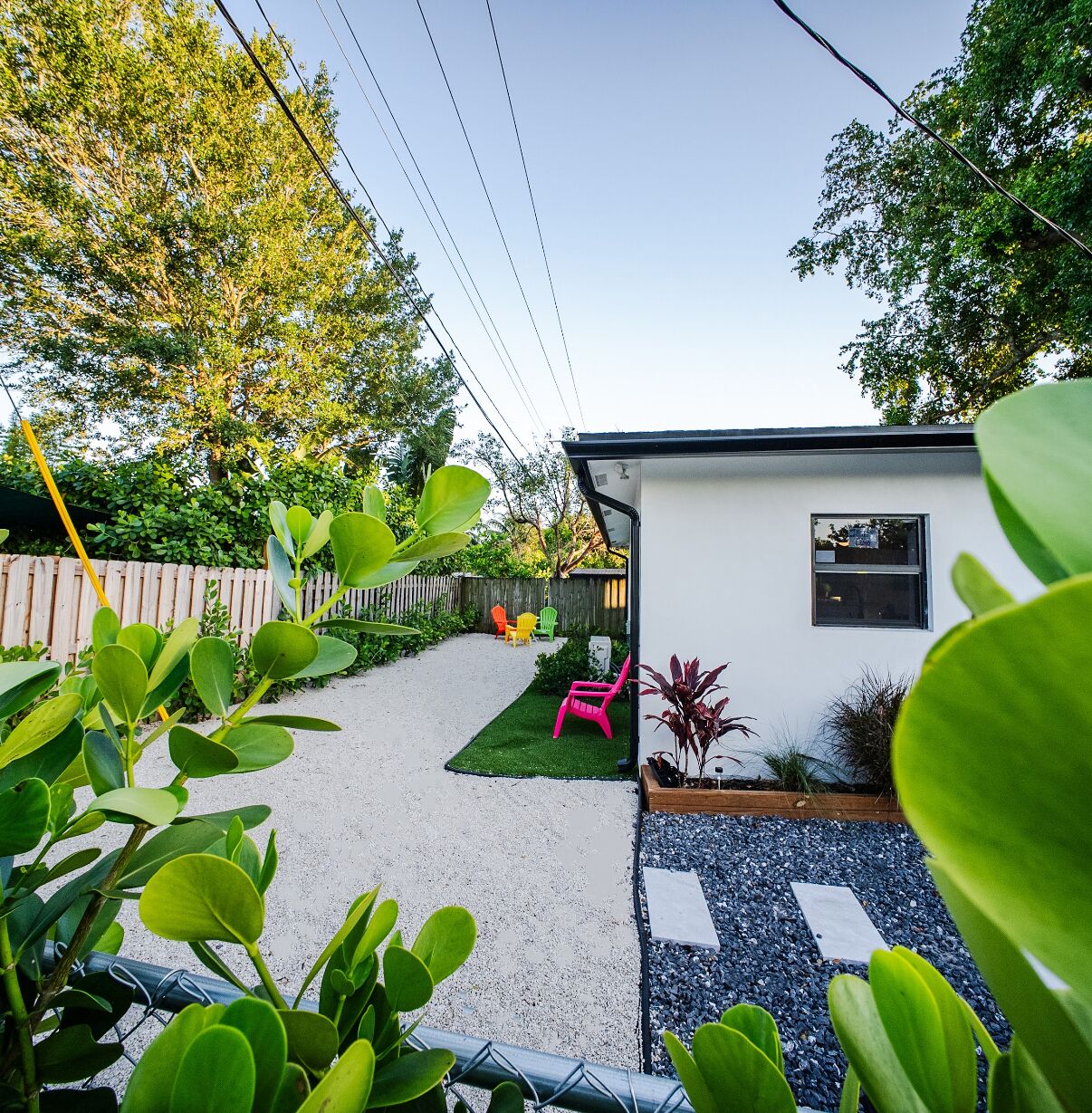 Un jardin avec un bâtiment blanc, une pelouse verdoyante et un chemin de gravier.