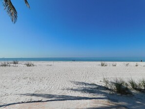 A wide sandy beach with a clear blue sky and calm sea. - Amazing Gulf views from the10th floor Beach front 2/2 condo at Riviera Club (Fort Myers Beach)