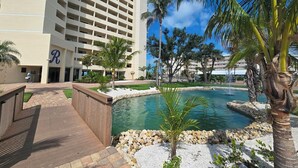 A hotel with a pool, palm trees, and a clear blue sky.