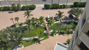 A landscaped courtyard with palm trees, a small pond, and a bridge.