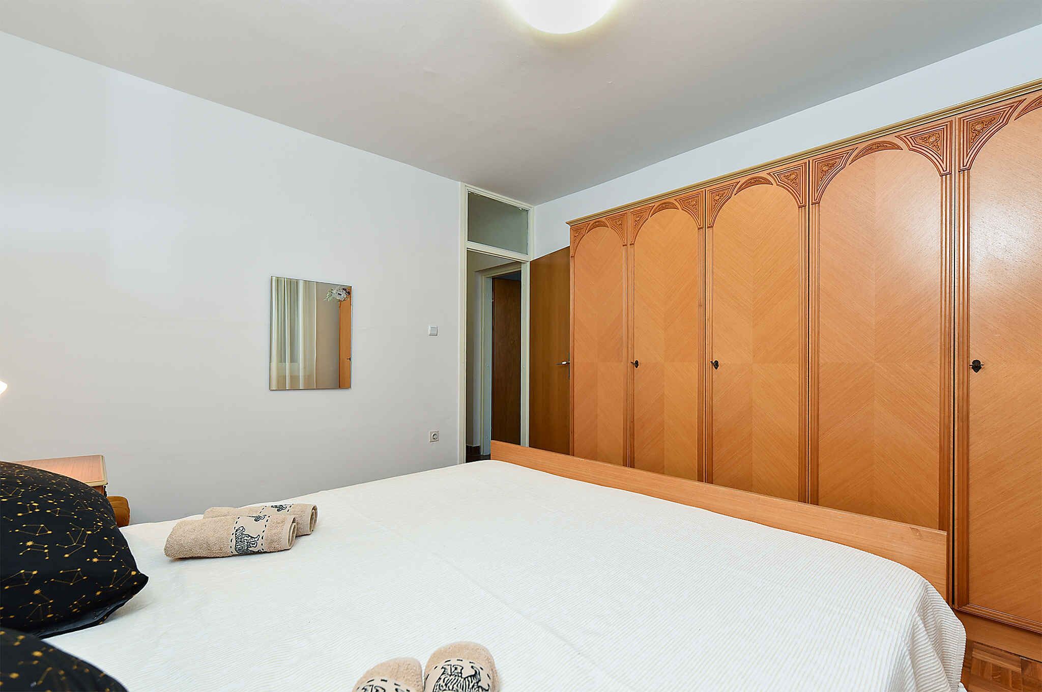 A bedroom with a bed, a wardrobe, and a mirror on the wall.