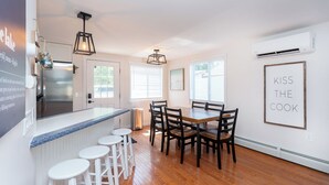 A modern kitchen with a bar area, wooden flooring, and a dining table with chairs. - Charming 3-bedroom house in Conesus with lake access and dock for boat (Conesus)