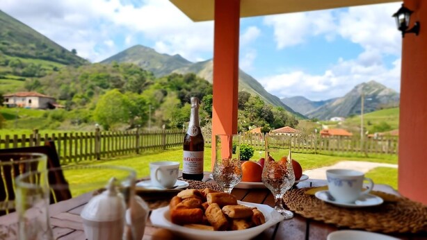 A table set for breakfast with a bottle of Il Gaieto wine, two glasses, a plate of pastries, and a cup of coffee.