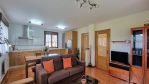 A modern living room with a sofa, TV, and dining area.