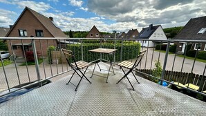 Un balcon avec une balustrade en métal, une petite table et deux chaises.