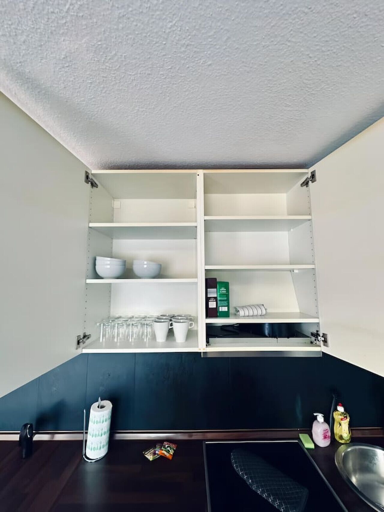 A kitchen with open shelving, a sink, and a dark countertop.