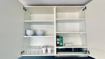 A kitchen with open shelving, a sink, and a dark countertop.
