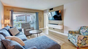 Un salon comprenant un canapé, un fauteuil, une table basse, un téléviseur et une chaise à motifs.