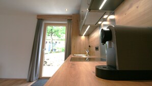 A modern kitchen with a wooden countertop, a built-in stove, and a window with curtains. - Hohe Salve by Interhome (Wildschönau)
