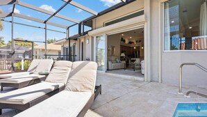 A poolside area with lounge chairs and a glass-enclosed patio.