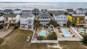 Una zona residenziale sul lungomare, con case, una piscina e vista sulla spiaggia.