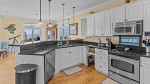 Una cucina moderna con mobili bianchi, un piano cottura in acciaio inossidabile e un forno a microonde.